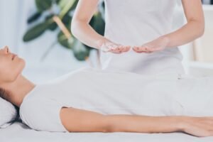 cropped shot of calm young woman receiving reiki healing treatment on stomach