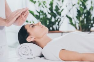 cropped shot of calm young woman with closed eyes receiving reiki treatment